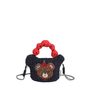 Dettaglio borsa di peluche blu con manico rosso ondulato e patch di orsetto cartone