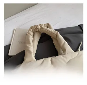 Detail shot of the beige quilted tote bag showing soft padded handles and wavy stitching