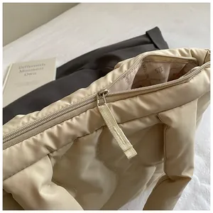 Detail view of beige quilted puffer tote showing secure zipper closure and printed lining