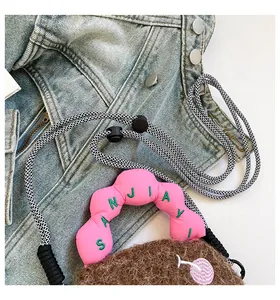 Dettaglio del manico rosa a forma di nuvola con ricamo verde su borsa morbida marrone