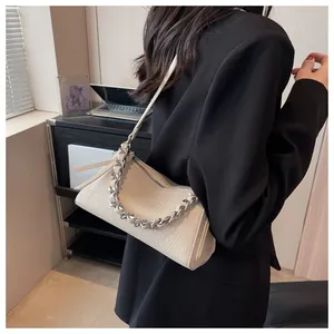 Detail der cremeweißen Ledertasche mit silberner Kette und schwarzem Anzug für Damen