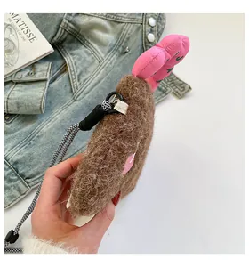Dettaglio borsa di peluche marrone con ciondolo a cuore rosa e tracolla intrecciata