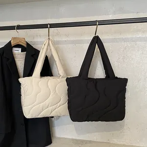 Quilted padded tote bag in cream and black colors featuring wavy nylon stitching patterns