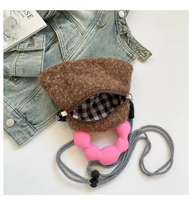 Dettaglio borsa di peluche marrone con manici ondulati rosa e fodera a scacchi bianchi e neri