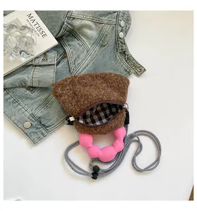 Dettaglio borsa a tracolla in peluche marrone con manico rosa e fodera a scacchi