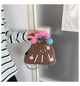Dettaglio di borsa in peluche marrone con viso ricamato e manici imbottiti rosa