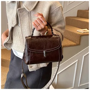 Detail of dark brown retro leather crossbody bag with ethnic woven wide strap