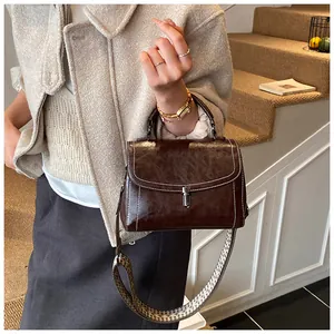 Detail of vintage brown leather handbag with contrast stitching and patterned wide strap