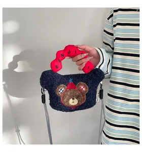 Dettaglio borsa orsetto di peluche blu navy con manico rosso e tracolla intrecciata