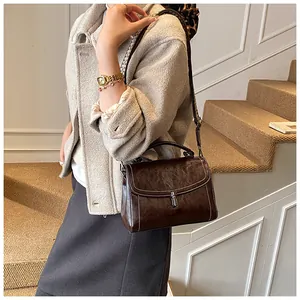 Detail of dark brown retro crossbody bag featuring contrast stitching and houndstooth strap