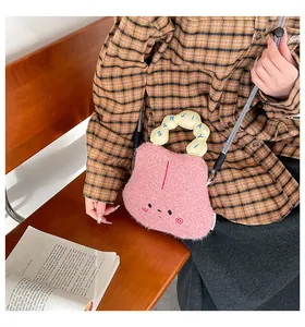 Dettaglio della borsa a tracolla in pile rosa con ricamo cartoon e tracolla intrecciata