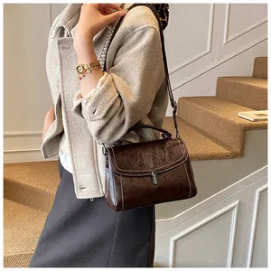 Detail of dark brown vintage crossbody bag with woven strap on a minimalist staircase