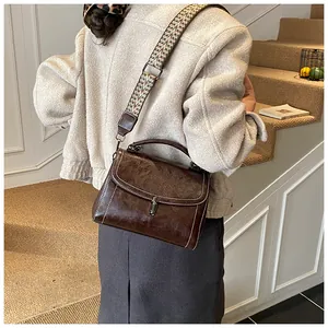 Close-up of vintage brown leather bag with ethnic style woven wide strap and silver lock