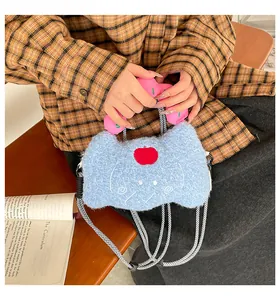 Dettaglio della borsa in peluche a forma di gatto con ricamo a mela e manici rosa