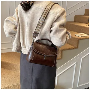Detail of vintage brown crossbody bag with white stitching and ethnic woven strap