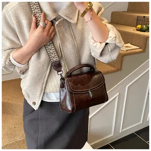 Detail view of coffee leather crossbody bag with ethnic patterned wide strap and metal lock