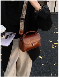 Detailed view of vintage brown leather bag with ethnic jacquard wide strap on a model