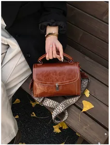 Retro brown bag with contrast stitching and bohemian woven strap on autumn bench