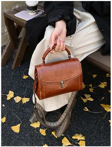 Detail of retro brown leather crossbody bag with ethnic patterned wide woven strap