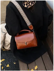 Detail view of brown leather crossbody bag with ethnic woven strap and contrast stitching
