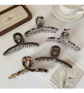 Vue détaillée de grandes pinces à cheveux motifs marbre et léopard dans un plateau en bois