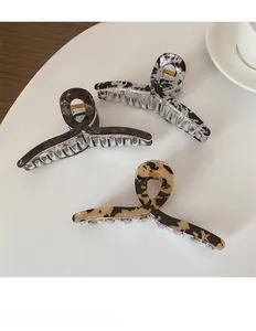 Détail de trois pinces à cheveux en acétate aux motifs léopard, marbre et écaille
