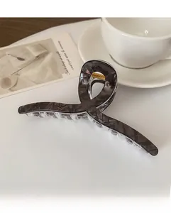 Détail de la pince à cheveux motif marbre gris avec ressort doré sur un plateau blanc