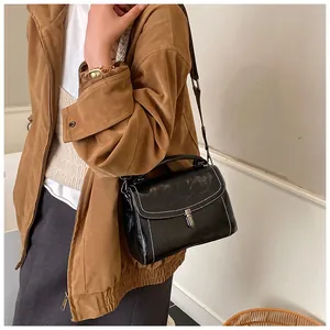 Detail of vintage black square crossbody bag with white contrast stitching and metal lock