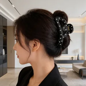 Grande pince à cheveux noire avec motifs floraux blancs portée sur un chignon élégant