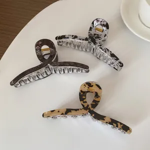 Trois pinces à cheveux à motif léopard et marbre sur une table blanche épurée