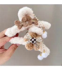 Détail de pince à cheveux en peluche crème avec nœuds, dentelle et perles à pompon