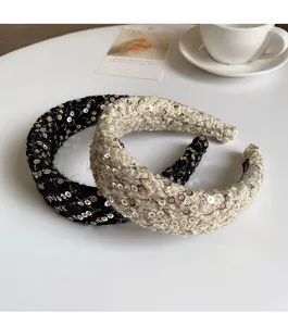 Detail of tweed plaid headbands with sequins in black and cream on a white table