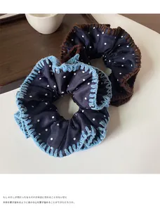 Detail of dark blue polka dot scrunchies with contrasting crochet trim on white table
