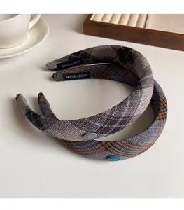 Detail view of plaid padded headbands with handmade labels on a cream table