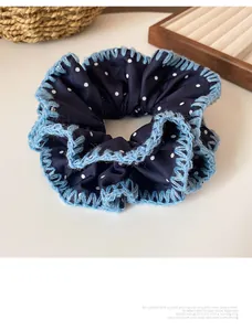 Detail of navy blue polka dot scrunchie with light blue crochet trim on a wooden tray