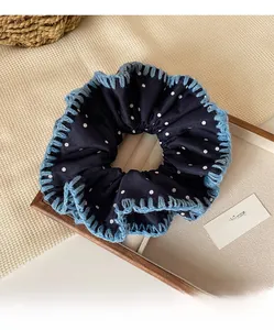 Detail of navy blue polka dot scrunchie with crochet trim on wooden tray