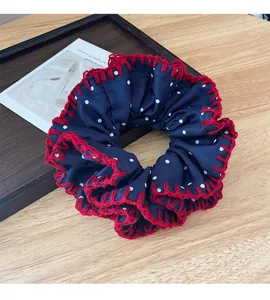 Close-up of blue polka dot scrunchie with red crochet lace on a wooden surface