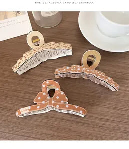 Trois pinces à cheveux à nœud marron avec pois sur un bureau en bois avec tasse à café