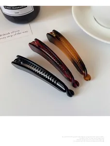 Détail de trois barrettes bananes brillantes en noir, écaille et ambre de résine