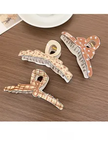 Détail de trois pinces à cheveux à motifs nœuds marron sur un fond en bois sombre