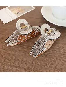 Pinces à cheveux à pois marron et beige sur un bureau en bois avec tasse à café