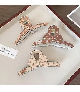 Détail de pinces à cheveux à nœuds marron avec motifs à pois et carreaux sur plateau
