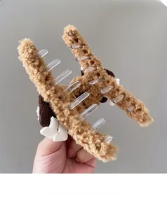 Détail d'une pince à cheveux en peluche mocha avec fausse fourrure douce et petit nœud blanc