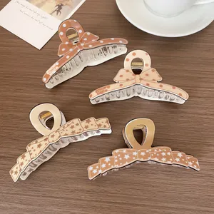 Pinces à cheveux nœuds marron et beige avec pois et étoiles sur fond en bois