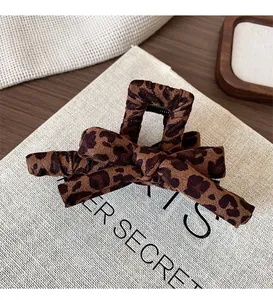 Detail of leopard print bow hair claw clip on canvas material background with natural lighting