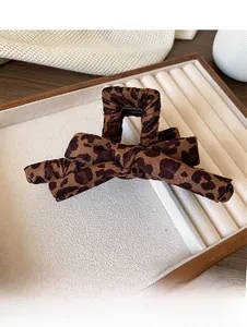 Detail of leopard print fabric bow hair claw clip with soft knitted texture on display