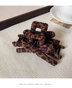 Detail showing leopard print bow hair claw clip with plush fabric and sturdy spring