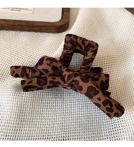 Detail of leopard print bow hair claw clip with fabric texture on mesh background