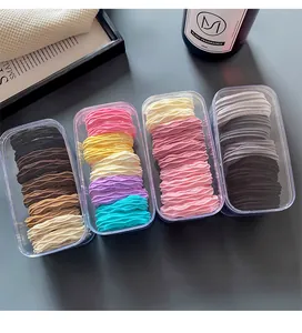 Macro detail of high-elasticity braided hair ties set in clear storage boxes