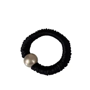 Coletero plisado negro elegante con una cuenta metálica de color champán